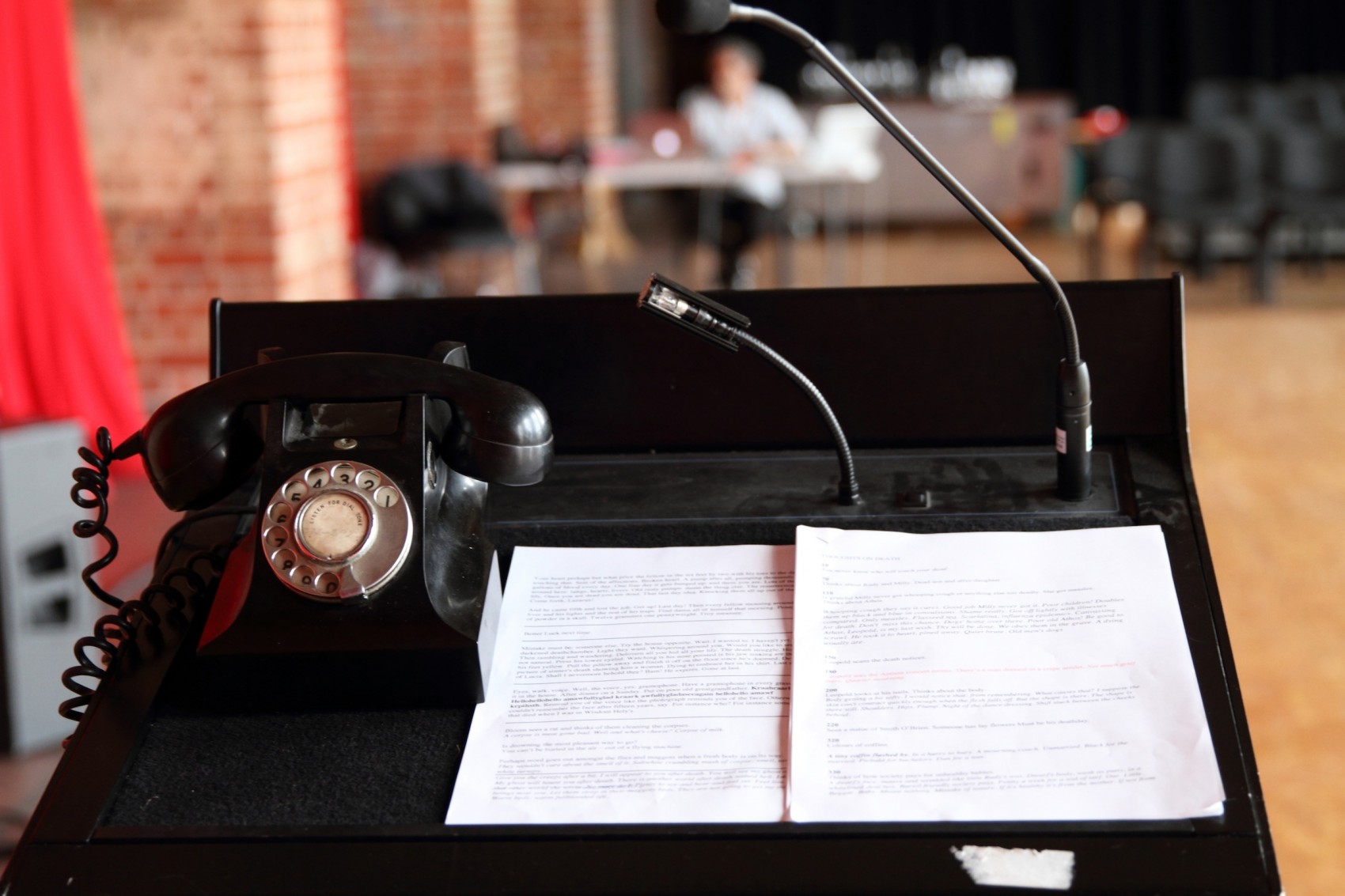 Old fashioned black telephone on stand with papers against a blurred room background