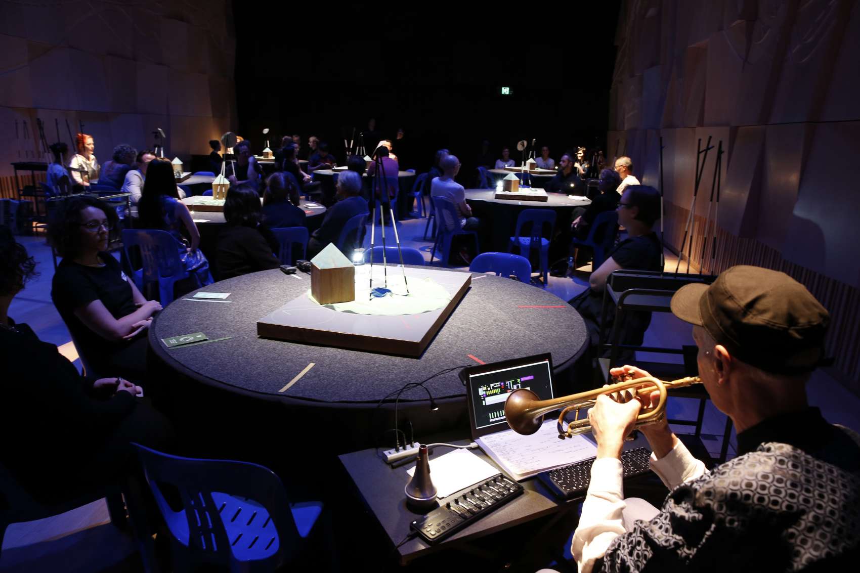 A performance space with audience seated around round tables