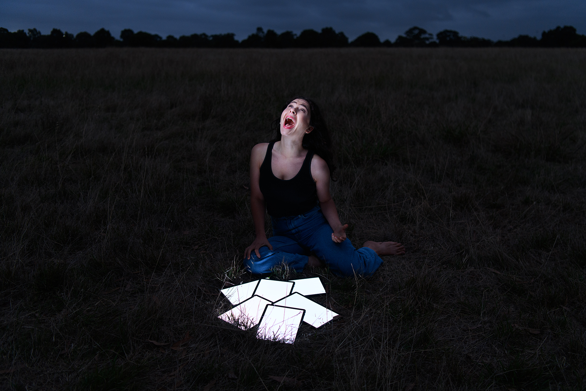 A woman in a field with a number of lit up tablets